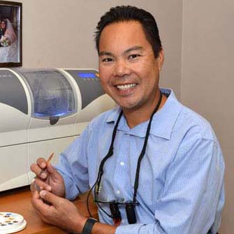 Dr. Joe Nguyen in the dental office smiling while working