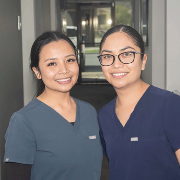 Two of our dental assistants smiling while hugging each other