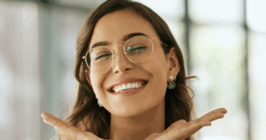 A young female with glasses happily smiles after her Cosmetic Dentistry.
