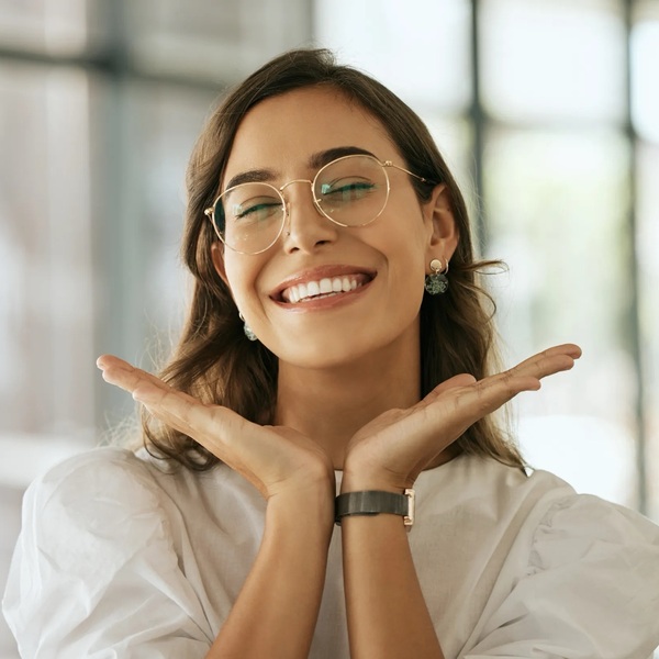 A brunette woman with glasses smiling 